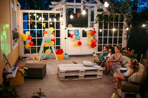 Perfect birthday party Group of children are sitting in the yard during a birthday party and watching a movie on a video projector happy birthday cousin images stock pictures, royalty-free photos & images