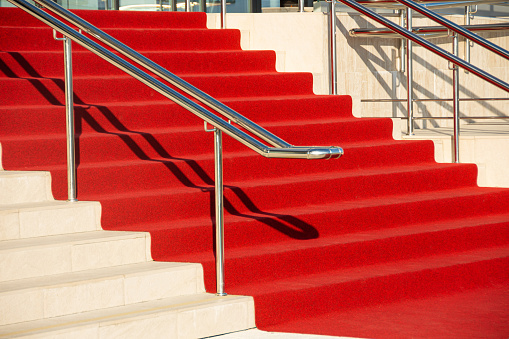 Red carpet on the stairs in a luxury interior outside outdoors and chromed shiny metal railings