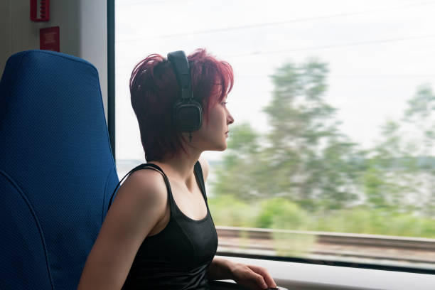 młoda kobieta jedzie pociągiem podmiejskim i patrzy przez okno na zewnętrzny krajobraz zamazany w ruchu - high speed train audio zdjęcia i obrazy z banku zdjęć
