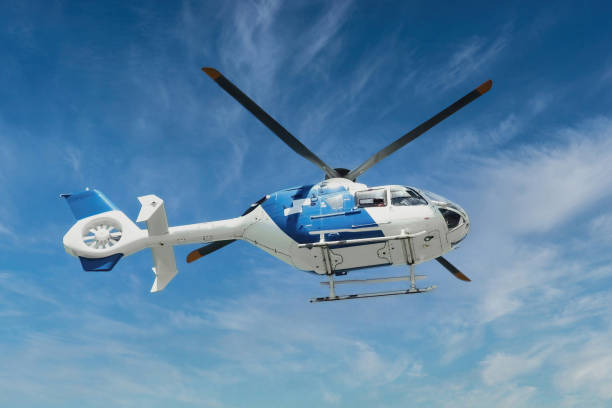 blau-weißer ambulanz-rettungshubschrauber, der mitten in der luft vor blauem himmelshintergrund fliegt - hubschrauber stock-fotos und bilder