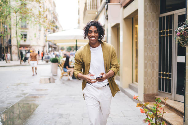 istock Positive young black guy surfing mobile phone while walking on street 1417056838