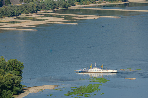 Ferry in the Rhine at low water level in summer 2022 with sandbanks in the foreground and background