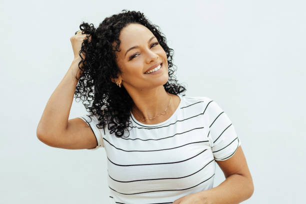 portrait d’une belle femme noire positive jouant avec ses cheveux - latin american and hispanic ethnicity isolated on white happiness cheerful photos et images de collection