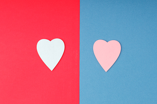 two-tone paper background with a red and blue heart on it. couple of lovers different colors