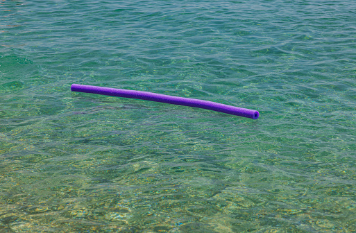 Close up view of swimming noodle ad assistant  on water surface. Greece.
