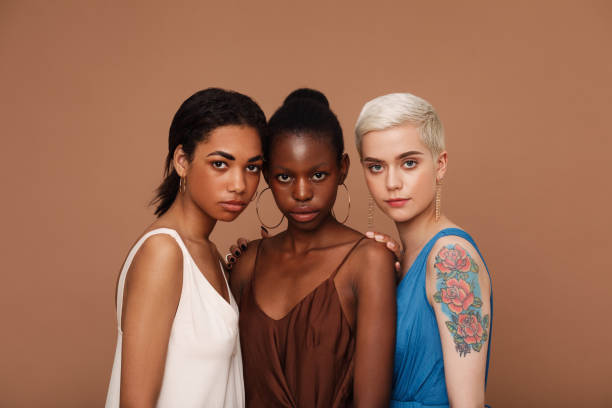 группа из трех женщин разных рас, стоящих вместе на коричневом фоне - st petersburg стоковые фото и изображения