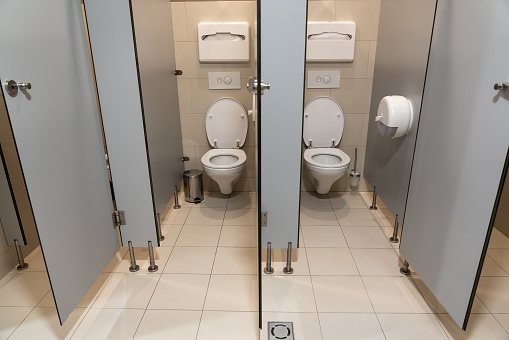 Row of empty toilet cubicles with open door in a public restroom.