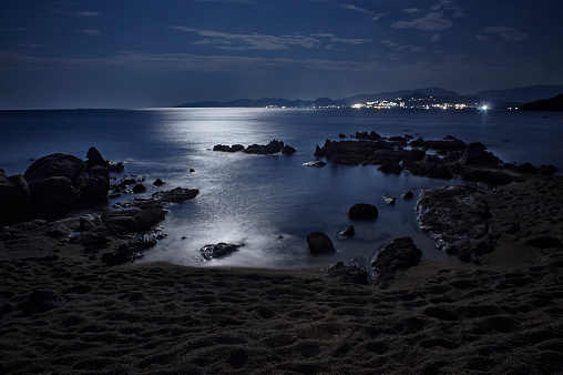 Night seascape of Capo Ferrato beach in southern Sardinia illuminated by the reflected light of the full moon: an exciting vision that evokes peace and tranquility.