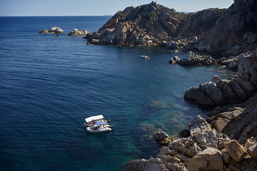 Natural bay of the coastline of southern Sardinia with two motorboats that are moored on the sea front. Typical tourist paradise that every year brings people to visit these magnificent places. Location Capo Ferrato.
