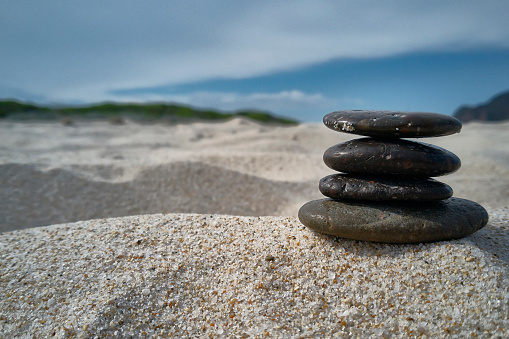 Stack of pebbles on the beach sand: Zen evocative image of inner peace, tranquility and general satisfaction.