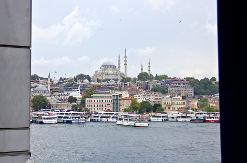 Istanbul,Turkey - August 10, 2022: Galata bridge linked eminönü and karaköy, there are lots of people on the bridge, lots of them are fishing, and beyond yhe bridge you see the süleymaniye mosque and fire tower in a cloudy summer day.