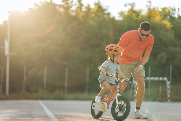 istock Father teaching his daughter to ride a bicycle 1417077449