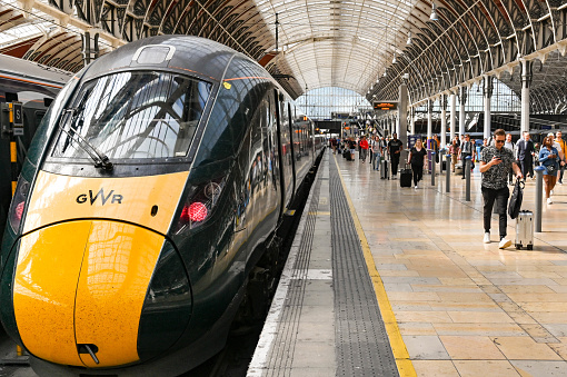 London, England - August 2021: Passengers arriving at London Paddington railway station. A Great Western Railway high speed train is alongside the platform