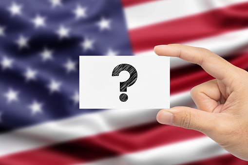 Holding note paper with Question Mark on blurred American flag background