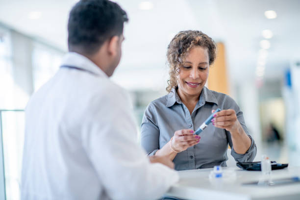 Doctor Explaining Diabetic Testing to a Senior Patient A Middle Eastern doctor explains how to test blood sugar levels to a Diabetic senior female patient. The patient is holding the lancet device and looking down at at. diabetes stock pictures, royalty-free photos & images