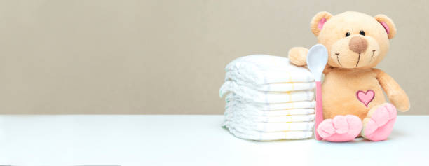 istock Stack of diapers with toy teddy bear with spoon on table. set for baby shower with copy space 1417085897