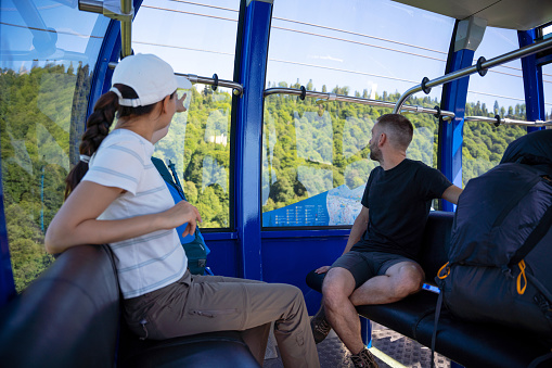 Heterosexual couple in the overhead cable car cabin on the way up to the mountains for hiking