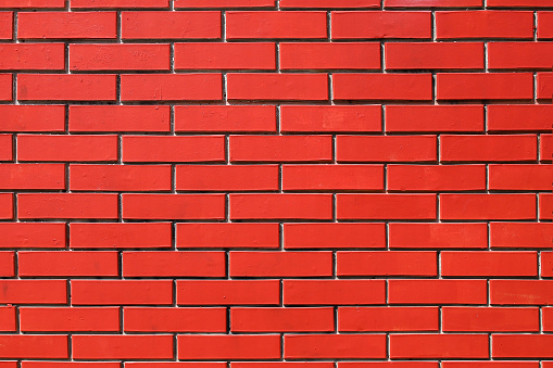Texture of a brick wall painted in bright red color as a background