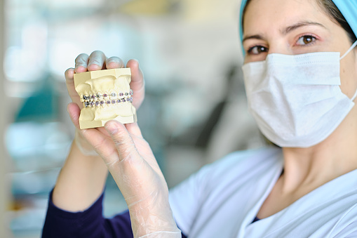 Dentist holding a dental prosthesis with brackets, close-up.