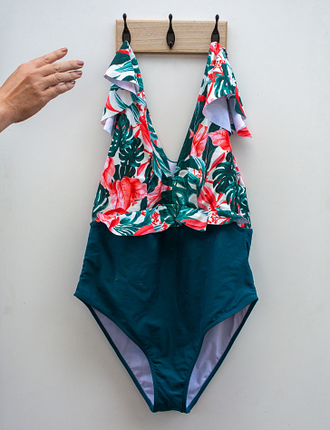 pulling a floral swimsuit from a coat rack