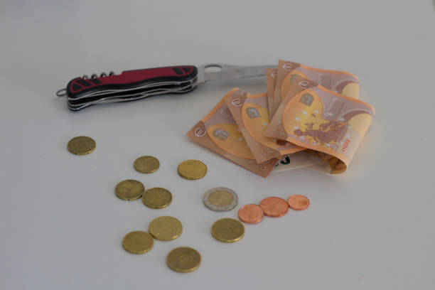 nůž s bankovkami umístěnými na bílém stole. bankovky jsou několik 50 eurobankovek spolu s mincemi - smrtící injekce - stock snímky, obrázky a fotky