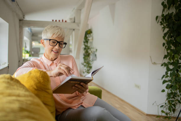 istock Happy woman reading book at home 1417102486