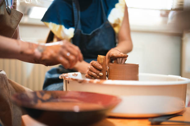 istock Two women shaping the clay on pottery wheel 1417102693