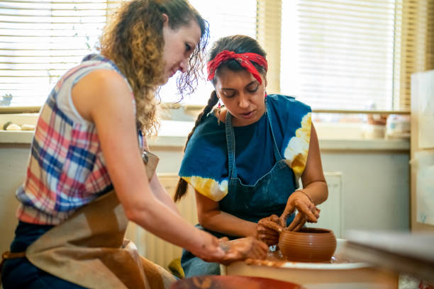 istock Two women shaping the clay on pottery wheel 1417102824