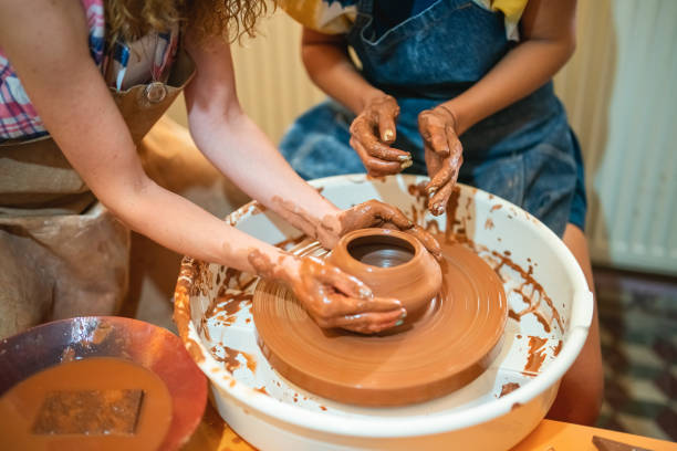 istock Two women shaping the clay on pottery wheel 1417103447