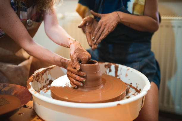 istock Two women shaping the clay on pottery wheel 1417104023