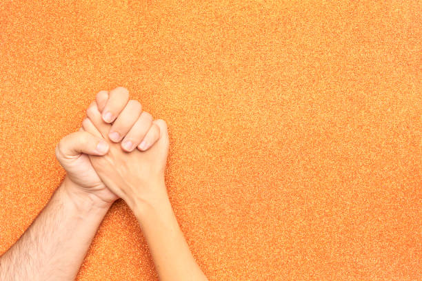 istock couple hands holding on orange glitter background 1417110036
