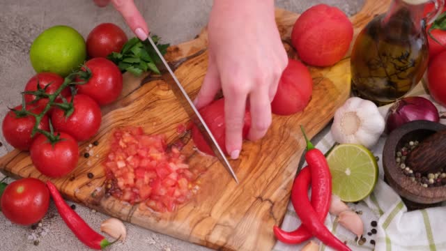 woman cutting peeled tomato using kitchen knife