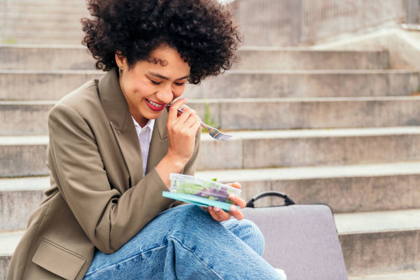 istock woman laughing and eating during a break from work 1417142582