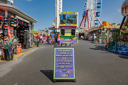 Ocean City, MD/USA - August 3, 2022: Staffing shortage sign at the ticket booth of the Jolly Roger at the Pier amuzement park at Ocean City, Maryland in summertime