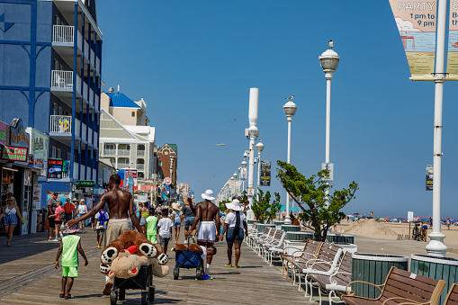 Ocean City, MD/USA - August 3, 2022: Families walk along the boardwalk lined with shops, restaurants and hotels at Ocean City, Maryland on a summer day