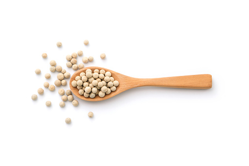 White pepper or peppercorns in wooden spoon isolated on white background , top view , flat lay.