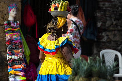 Cuenca, Ecuador - January 6, 2022: Plaza Civica in front of agriculture market '9 de Octubre'. Woman in traditional clothes for Azuay province with big basket crosses the square. Ecuador