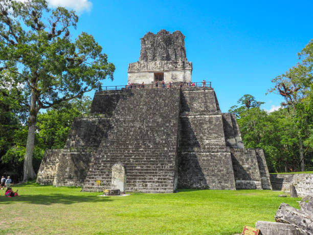 un tempio maya a tikal con turisti in piedi al livello più alto - mayan temple old ruin ancient foto e immagini stock