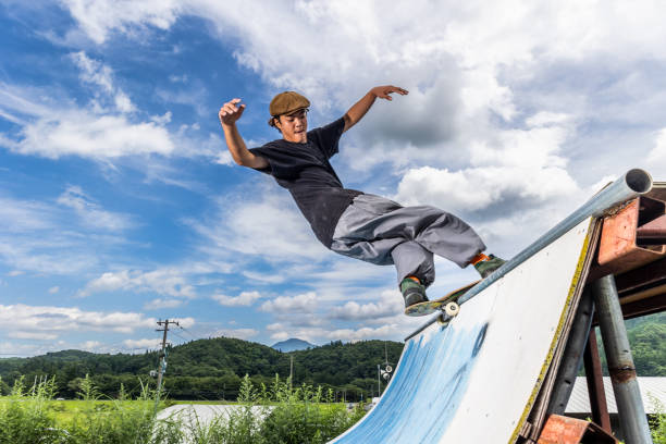 skateboarder faisant un trick sur un half-pipe - grinding photos et images de collection
