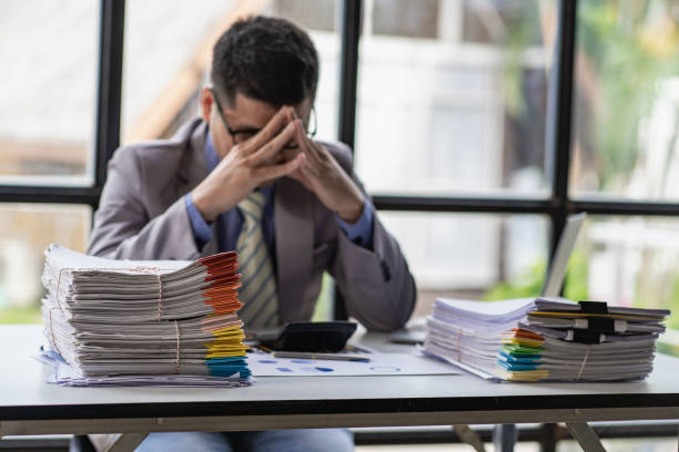 istock Businessman stressed with work with piles of unresolved documents on desk in office 1417184837