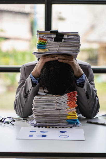 istock Businessman stressed with work with piles of unresolved documents on desk in office 1417184838