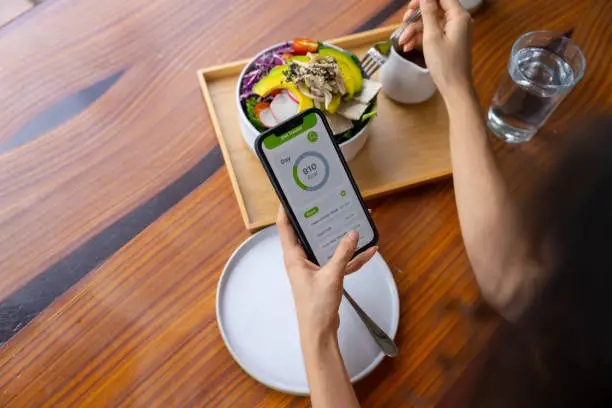 Photo of Vegetarian woman eating tofu salad and playing social media.