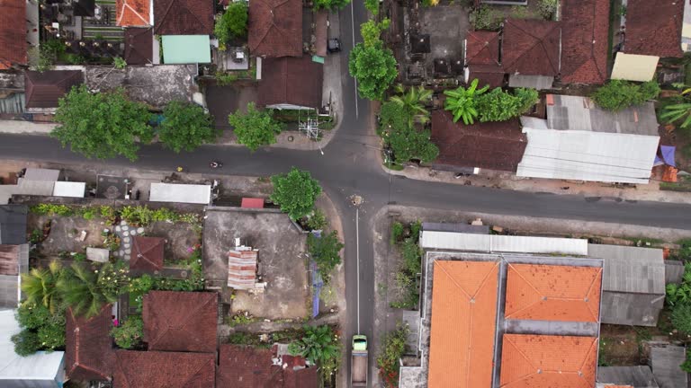 Top-down view of road crossing in Bali village, woman put canang sari