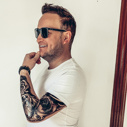 Young boy with an arm tattoo and sunglasses. White teeth and smile.