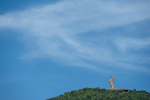 Under the blue sky, the bronze statue of God stands on the top of the mountain