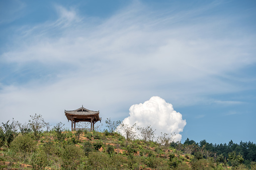 A pavilion on the hillside under the blue sky and white clouds