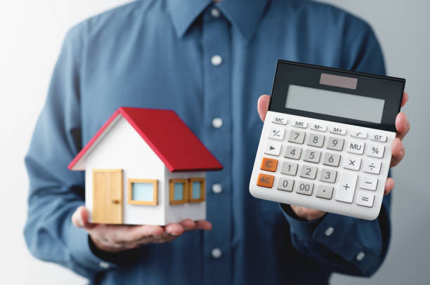 istock Man holding calculator and miniature house. 1417215493