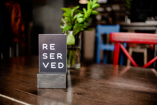 Reserved sign on a table in restaurant.Red chair and vase. Horizontal view several ojects.