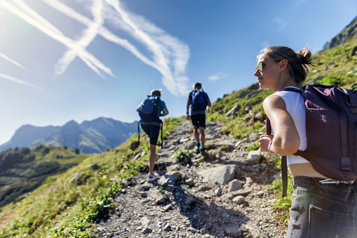 Three teenage kids are hiking in the Alps - Vorarlberg, Austria. They are walking on the footpath in the high mountains of Austria.\nCanon R5