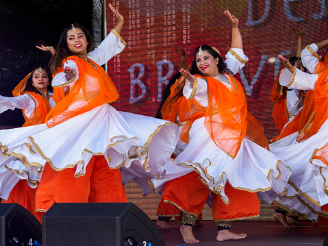 Aberdeen, Scotland, UK - August 21, 2022: Dancers with the Scottish-based group Desi Braveheart performing a Bollywood style routine at the Mela One-World Day in Westburn Park, Aberdeen.  The Mela is a free multicultural event held annually in the city offering dance and music performers from other cultures who live in Scotland an opportunity to show off their cultural heritage.